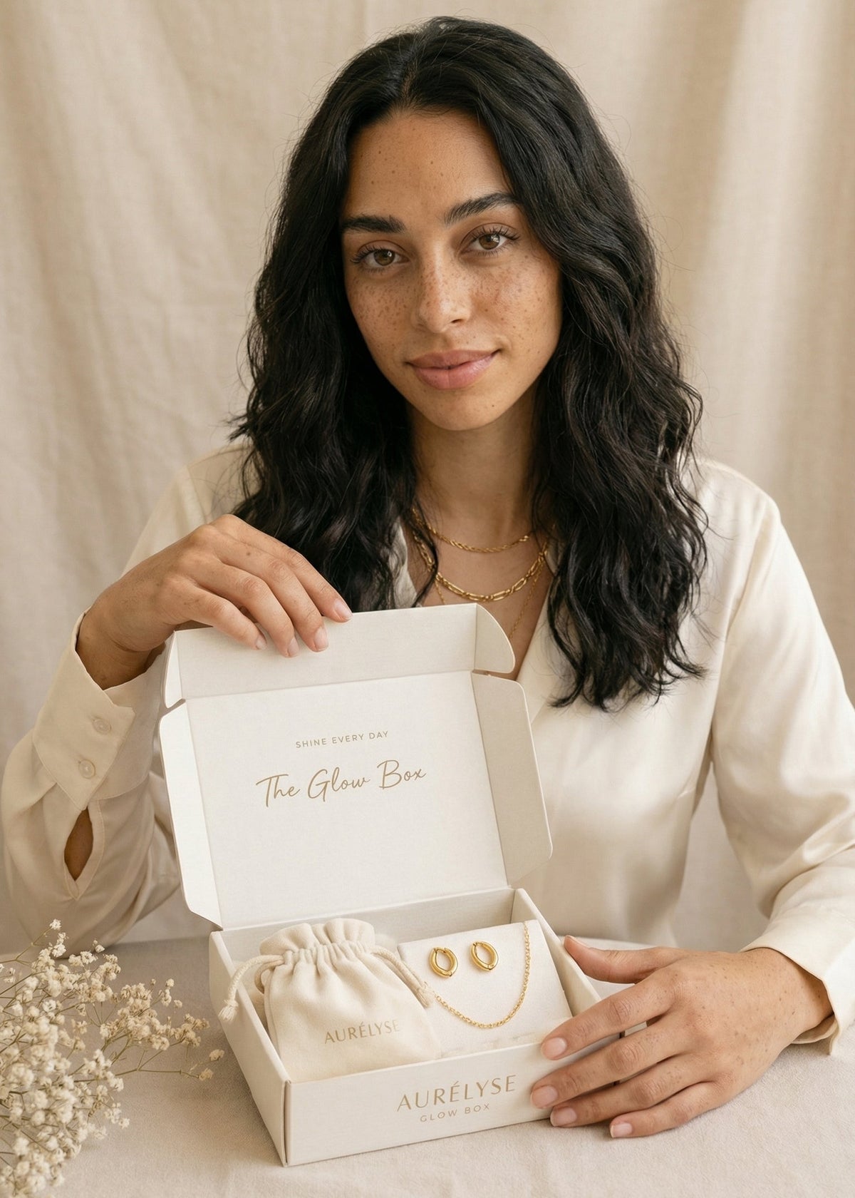 Woman holding a jewelry box with 'True Grit' branding on a beige background